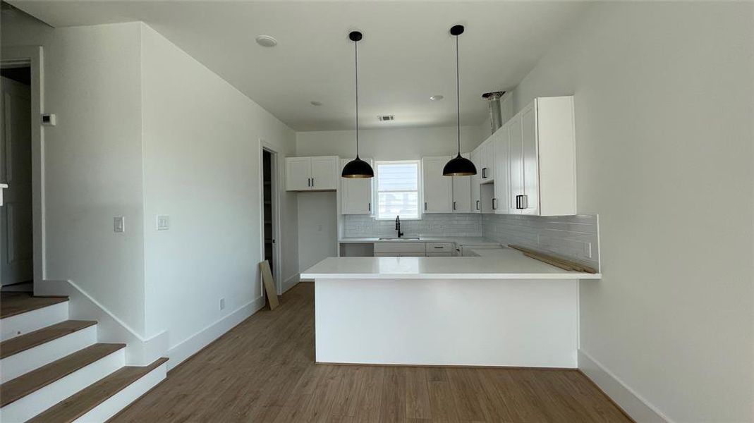 Modern kitchen space is well-lit with natural light and has a minimalist aesthetic.