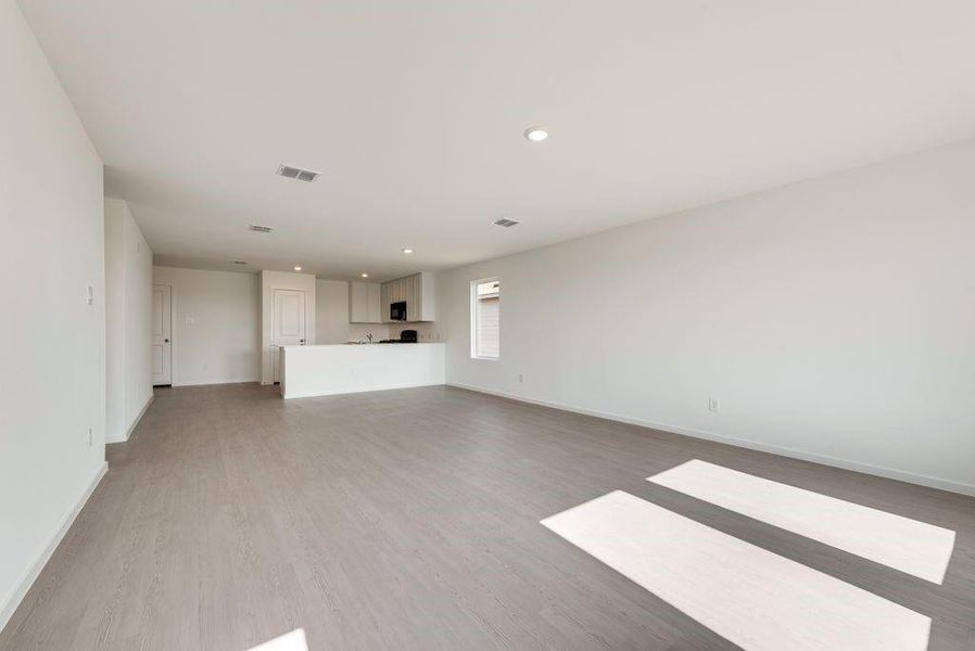 Unfurnished living room featuring light wood-type flooring, visible vents, baseboards, and recessed lighting