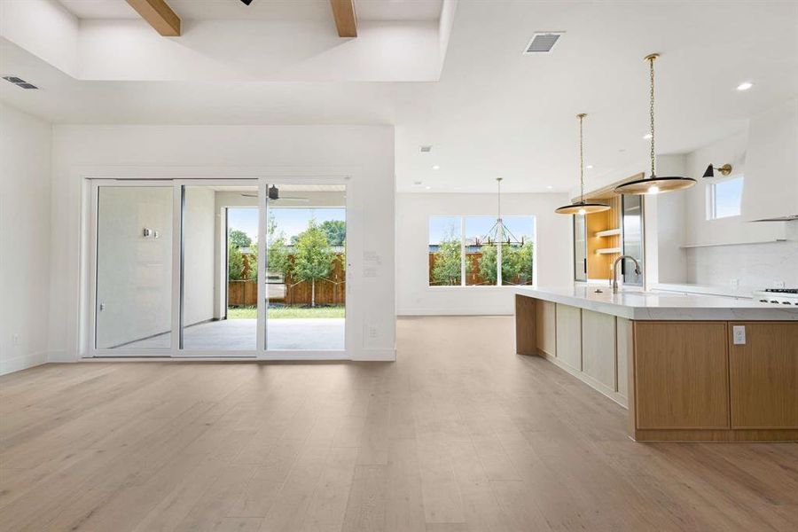 Kitchen featuring white cabinets, hanging light fixtures, sink, a kitchen island with sink, and light hardwood / wood-style floors