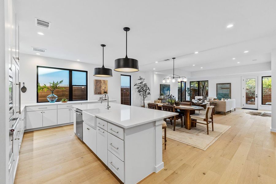 Kitchen with white cabinets, pendant lighting, healthy amount of natural light, a kitchen island with sink, and recessed lighting