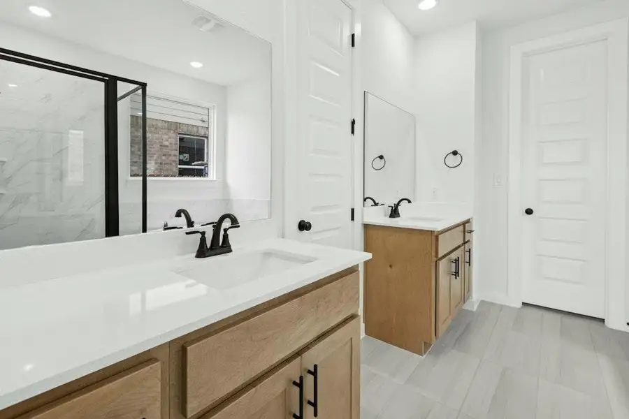 Full bathroom featuring two vanities, a marble finish shower, and recessed lighting