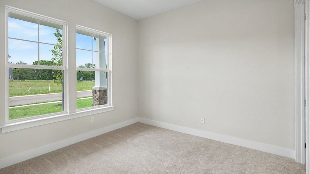 Secondary bedroom with windows and carpet