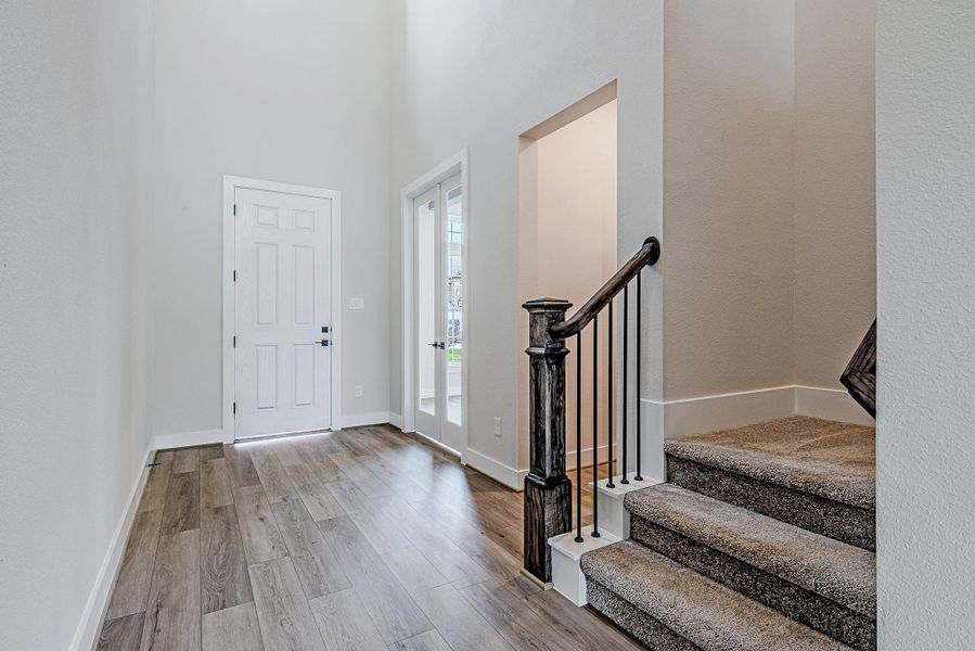 Welcoming entryway featuring wood-look flooring and a staircase with clean, modern finishes.