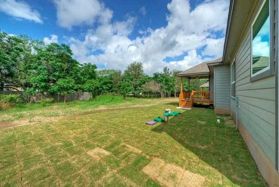A spacious backyard with mature trees, fresh sod, and a welcoming covered porch provides a tranquil outdoor retreat.