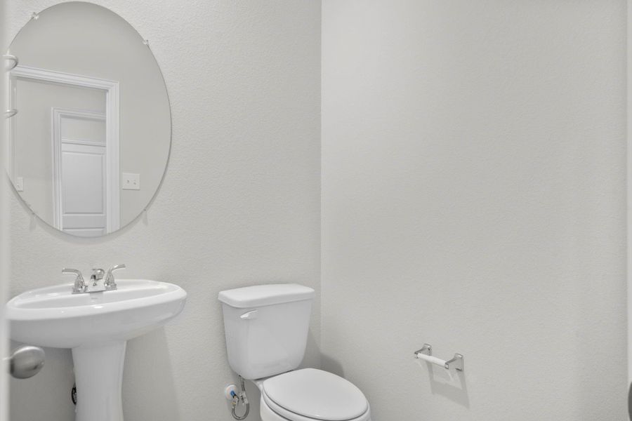 The stylish half bath on the first floor features a pedestal sink, framed mirror, and soft neutral tones that create a crisp and welcoming atmosphere for guests. Perfectly positioned for convenience and privacy near the main living areas. The stylish half bath on the first floor features a pedestal sink, framed mirror, and soft neutral tones that create a crisp and welcoming atmosphere for guests. Perfectly positioned for convenience and privacy near the main living areas.
