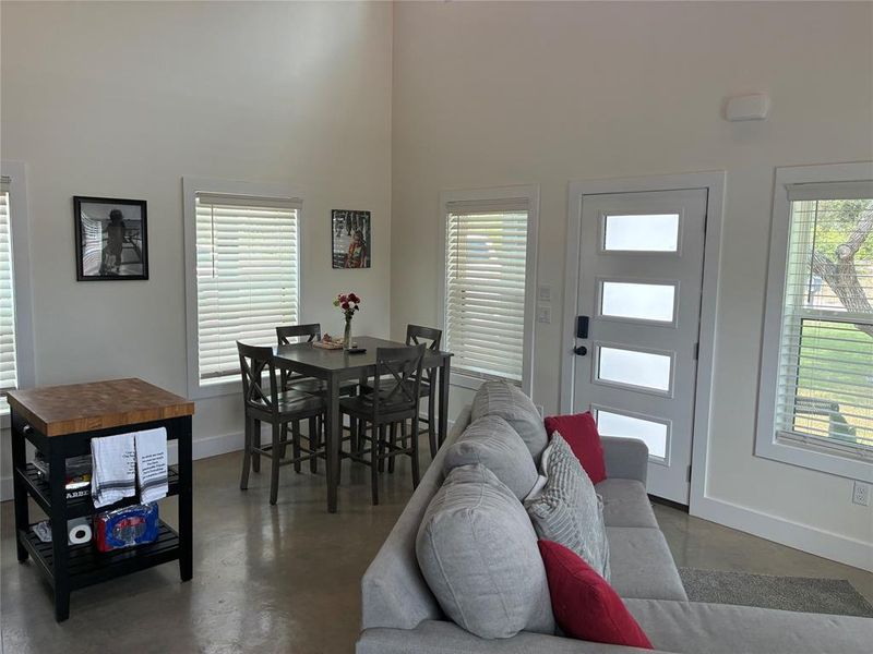 Living room featuring concrete floors, plenty of natural light, and a high ceiling