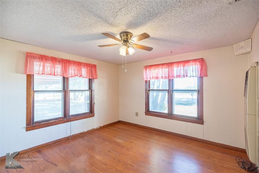 Empty room with light wood-style floors, ceiling fan, and a textured ceiling Empty room with light wood-style floors, ceiling fan, and a textured ceiling