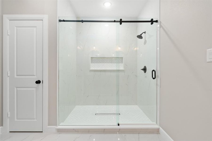 Bathroom with a marble finish shower and baseboards