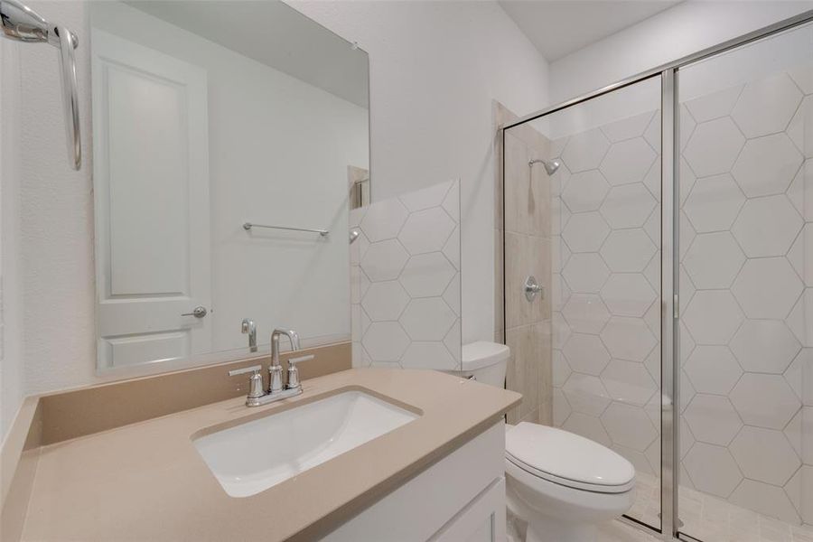 Bathroom featuring a shower with shower door, vanity, and toilet