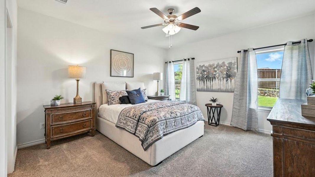 This bedroom features light-colored walls and carpet, with natural light entering through two windows