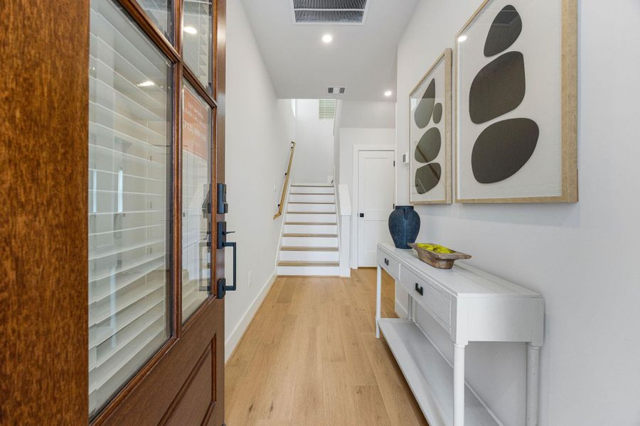 Step into elevated living in this beautifully designed 3-story home in Independence Heights featuring a bright, modern entryway with soaring ceilings, designer lighting, warm wide-plank hardwood floors, and sleek contemporary finishes