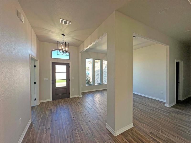 Foyer entrance featuring wood finish floors and a chandelier Foyer entrance featuring wood finish floors and a chandelier