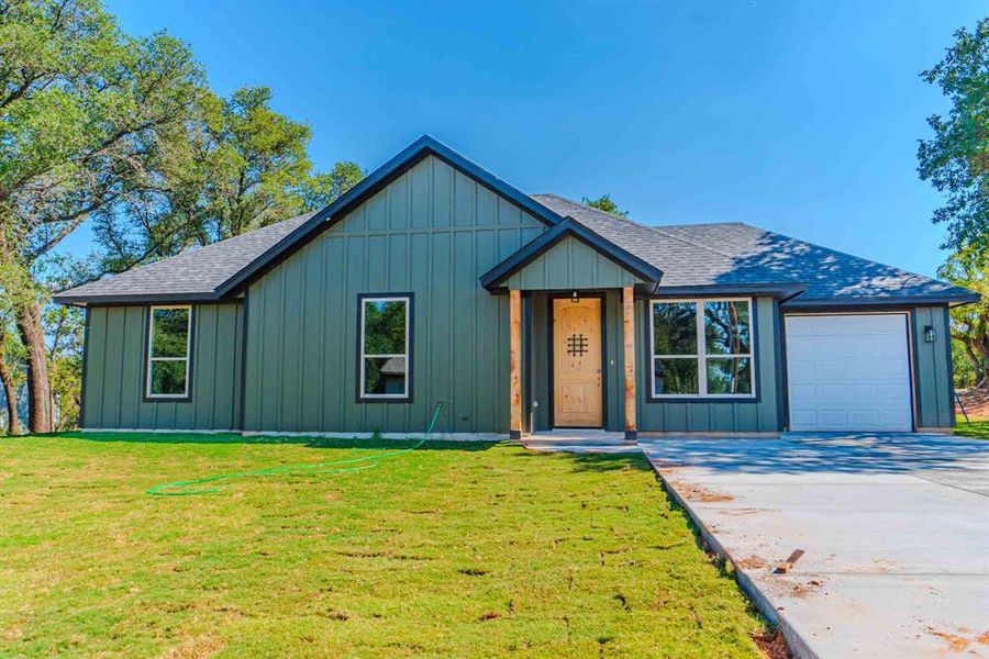 View of front of home with board and batten siding, a shingled roof, and a front lawn