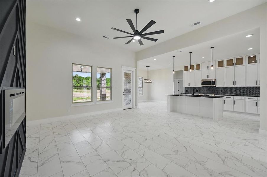 Kitchen featuring stainless steel microwave, open floor plan, dark countertops, a ceiling fan, and baseboards Kitchen featuring stainless steel microwave, open floor plan, dark countertops, a ceiling fan, and baseboards