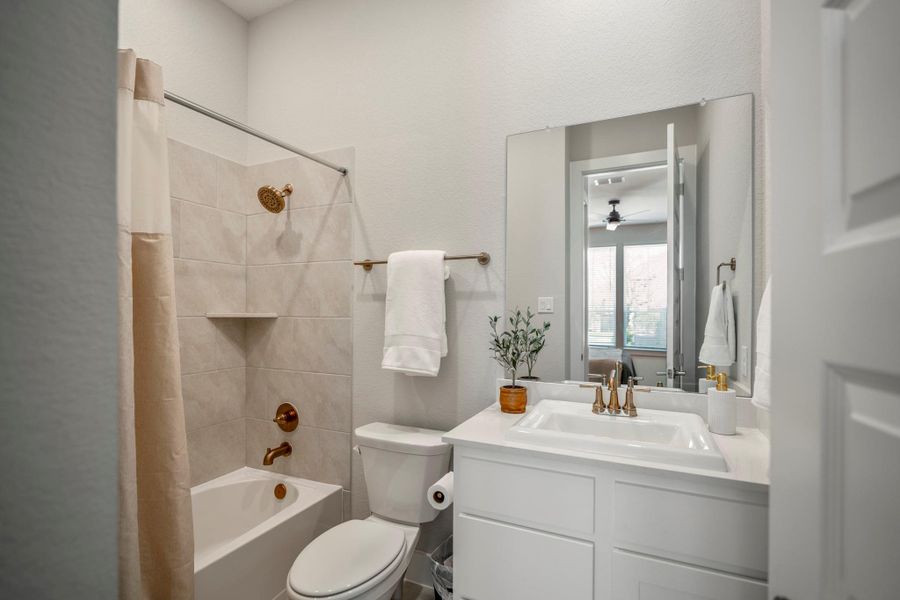 The private ensuite bathroom includes a quartz-topped vanity, full mirror, tub and shower combination and stylish fixtures, giving guests everything they need in a comfortable, private setting.