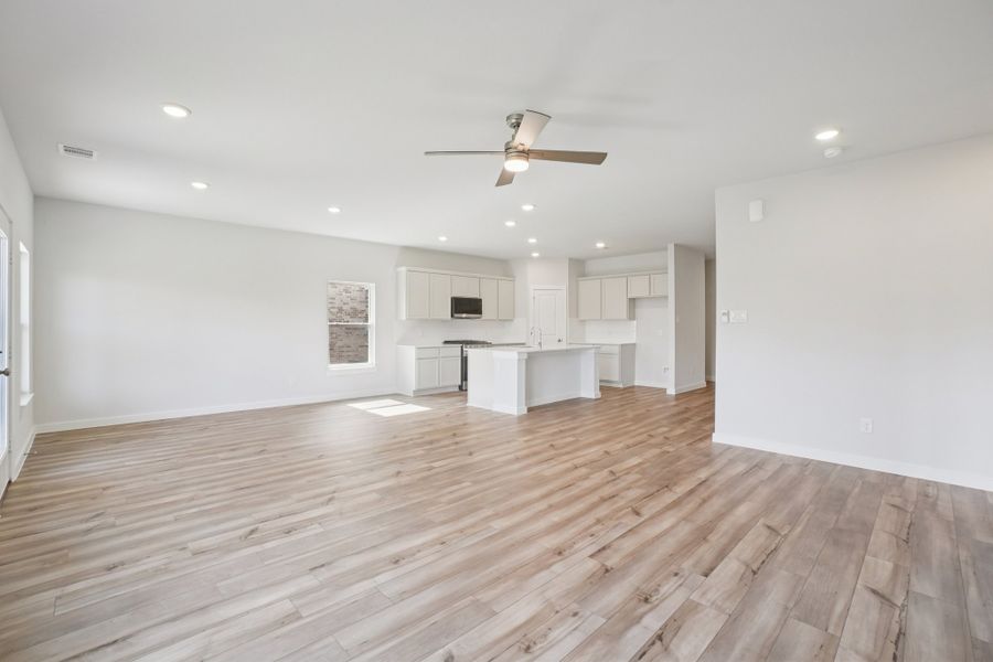 A large empty room with a wood floor and a ceiling fan.