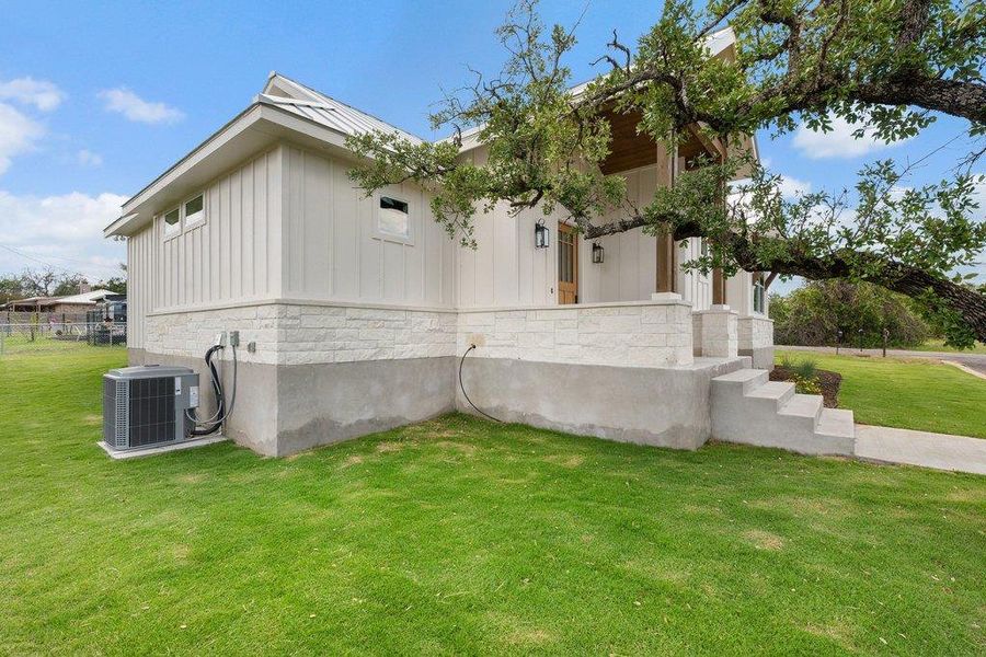 The property features white board and batten siding, a white stone veneer skirt, and a concrete foundation
