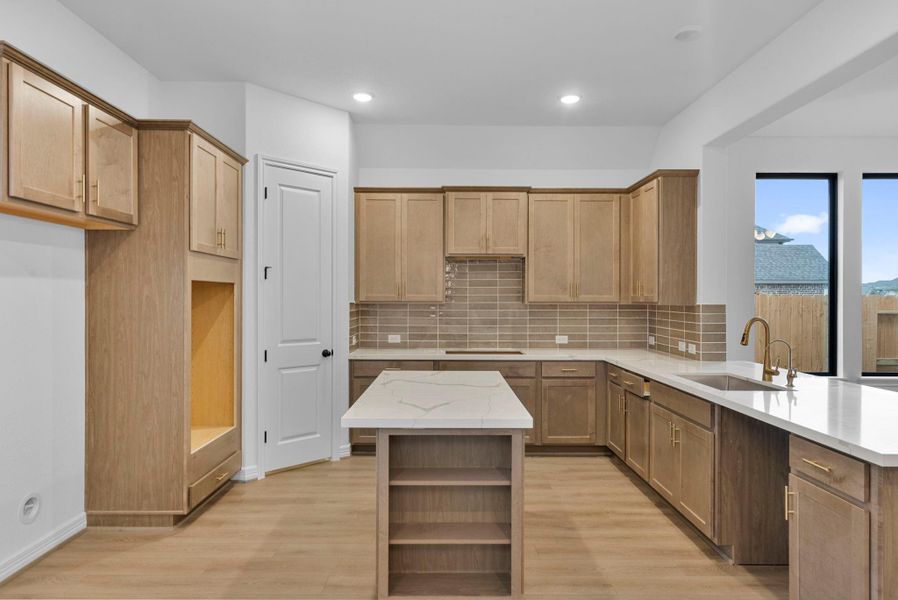 The harmony between the natural stained cabinets, beautiful quartz counters, and modern backsplash make a bold but serene statement.
