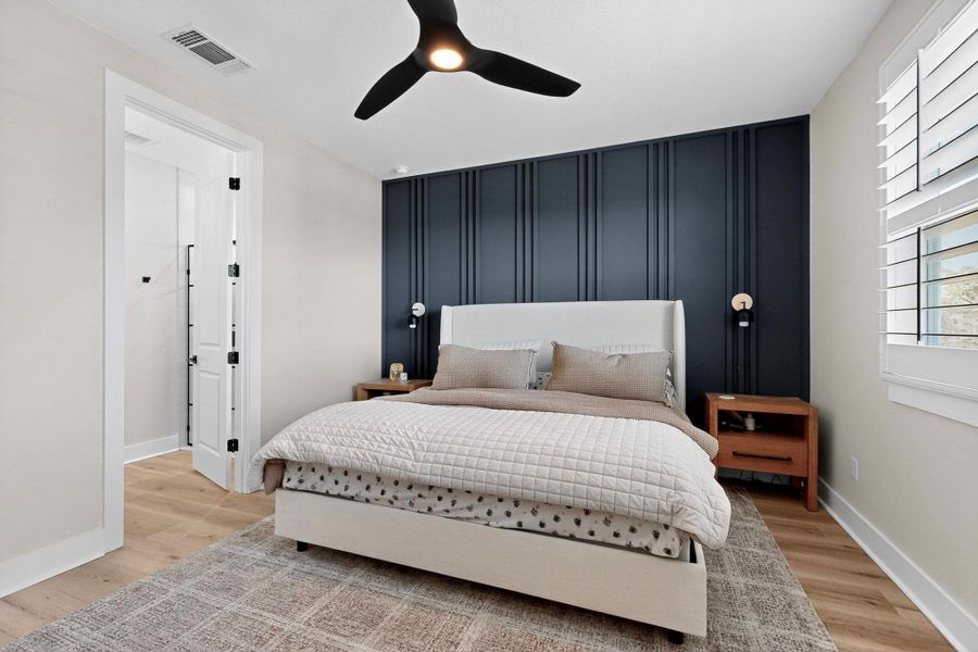 Primary Bedroom with an accent wall, light wood finished floors, and ceiling fan