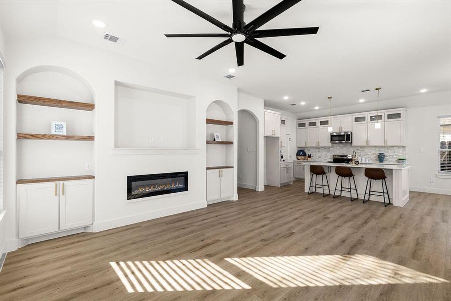 Living room featuring built in shelves, ceiling fan, and light hardwood / wood-style floors