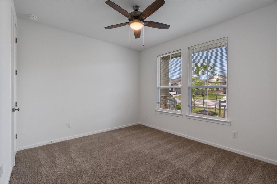 A well-lit bedroom with carpeting and a ceiling fan