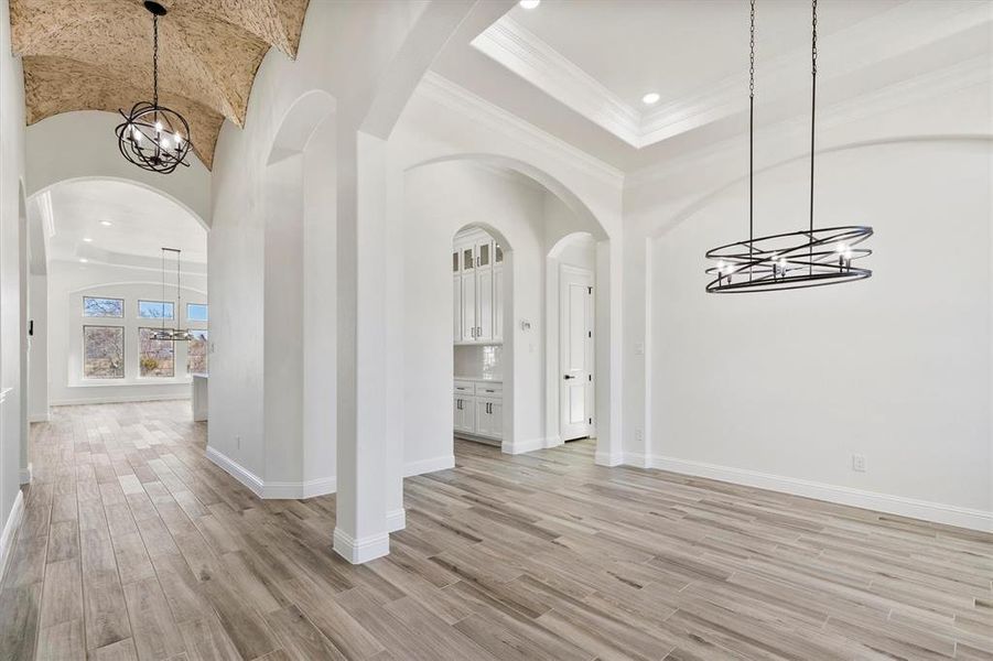 Formal dining area featuring crown molding, custom style floors, vaulted ceiling decorative lighting