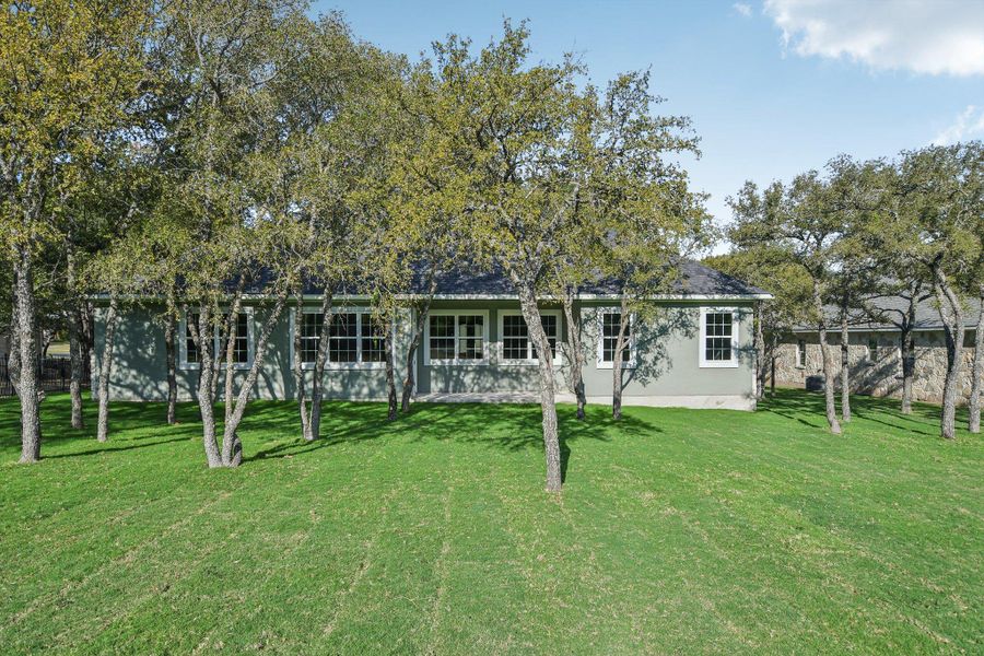 Back of house featuring a lawn and stucco siding