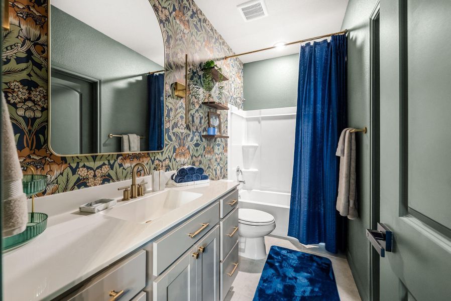 Full bathroom with vanity, shower / tub combo with curtain, wallpapered walls, and light tile patterned floors