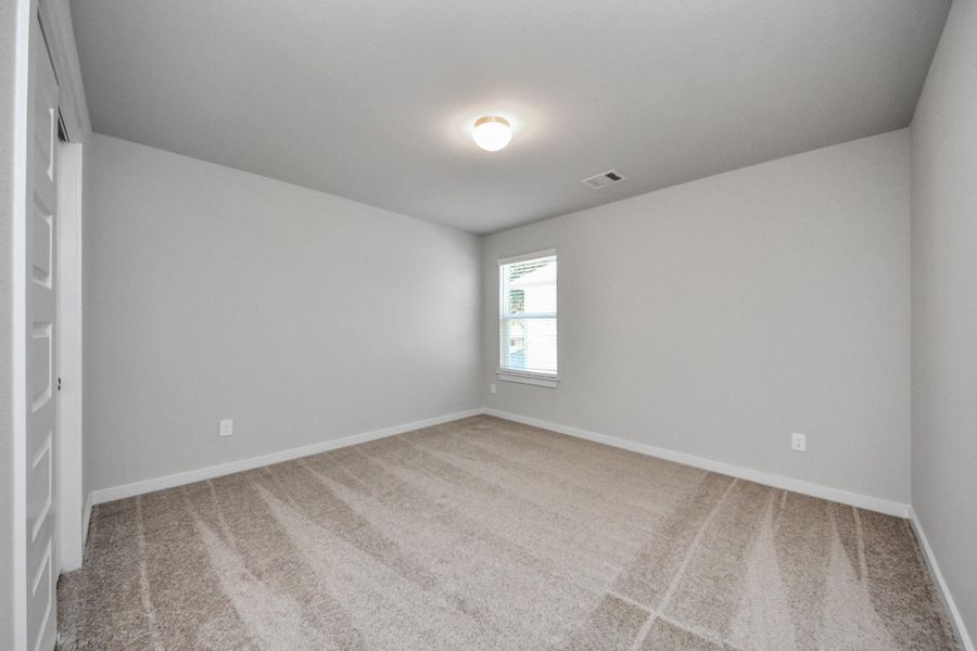 Secondary bedroom features plush carpeting, large windows that let in plenty of natural light, bright paint, and spacious closets. Sample photo of completed home with similar floor plan. Actual colors and selections may vary.