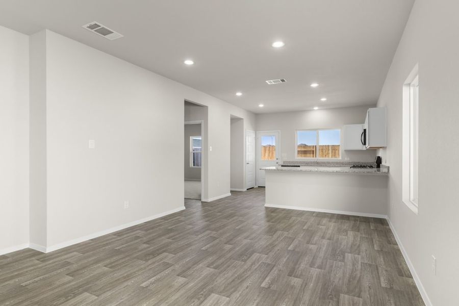 Image of a dining room area with beige walls, windows, a connecting kitchen and a back white door Image of a dining room area with beige walls, windows, a connecting kitchen and a back white door