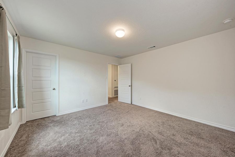 A spacious room featuring plush carpeting and a bright overhead light, offering a comfortable personal retreat.