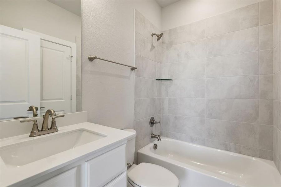 Full bathroom featuring toilet, tiled shower / bath combo, and vanity