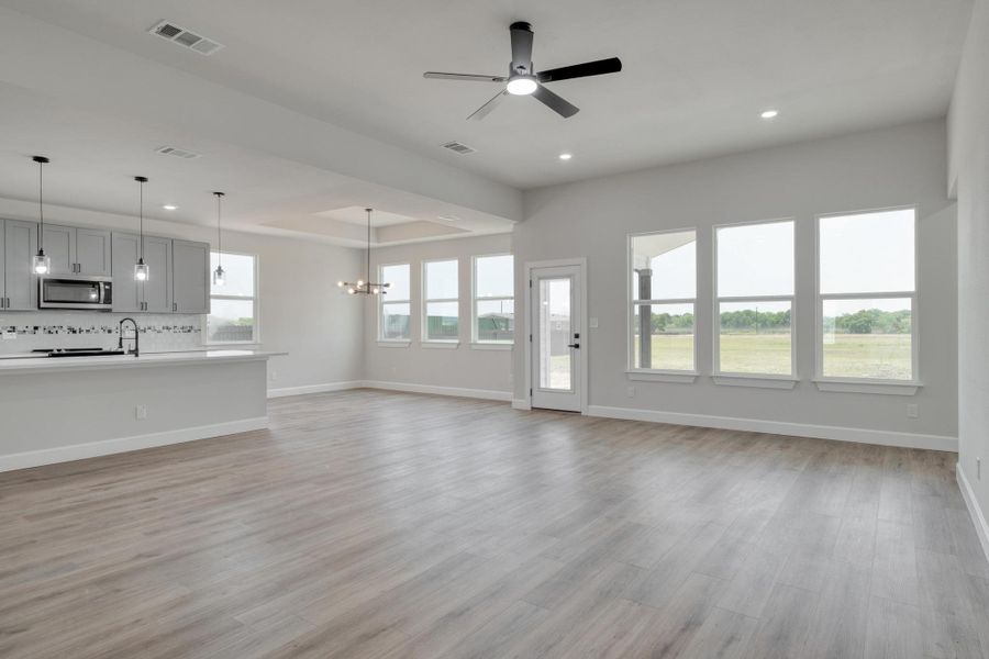 Unfurnished living room with recessed lighting, baseboards, a ceiling fan, light wood-style flooring, and a chandelier