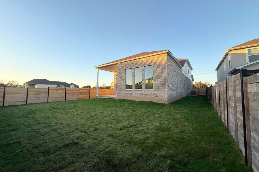 Rear view of house with a fenced backyard, brick siding, and a patio
