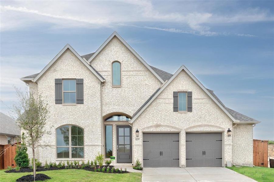 French country home featuring a garage and a front yard