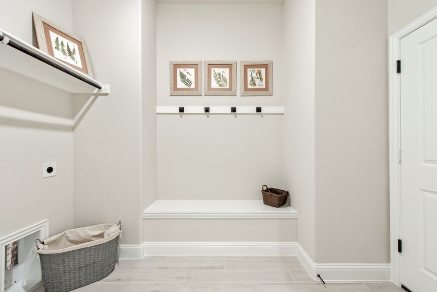 Mudroom with built-in bench, coat hooks, wall shelf, and wicker storage baskets on light tile floor Mudroom with built-in bench, coat hooks, wall shelf, and wicker storage baskets on light tile floor