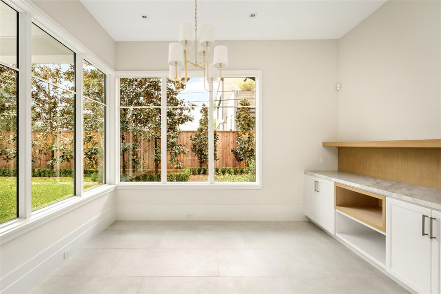 Sunlit breakfast room framed by expansive windows, featuring built-in storage with white oak rift accents and subtle under-cabinet lighting.