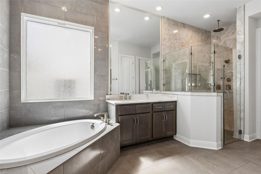 Luxurious bathroom retreat features a spacious soaking tub and a sleek, glass-enclosed shower.