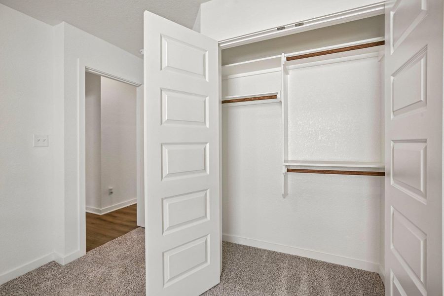 Functional built-in shelving and hanging rods maximize storage space within this bedroom closet.