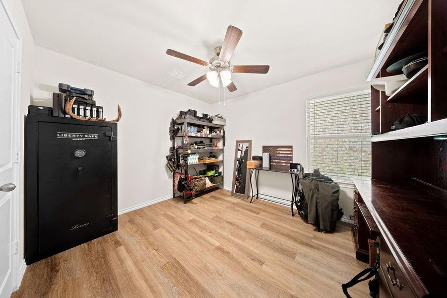 Interior room featuring wood-finish flooring, a ceiling fan with light, and a window with horizontal blinds Interior room featuring wood-finish flooring, a ceiling fan with light, and a window with horizontal blinds