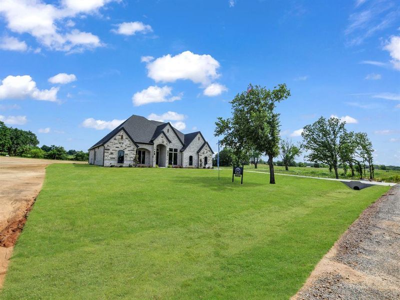 French country inspired facade with stone siding and a front lawn French country inspired facade with stone siding and a front lawn