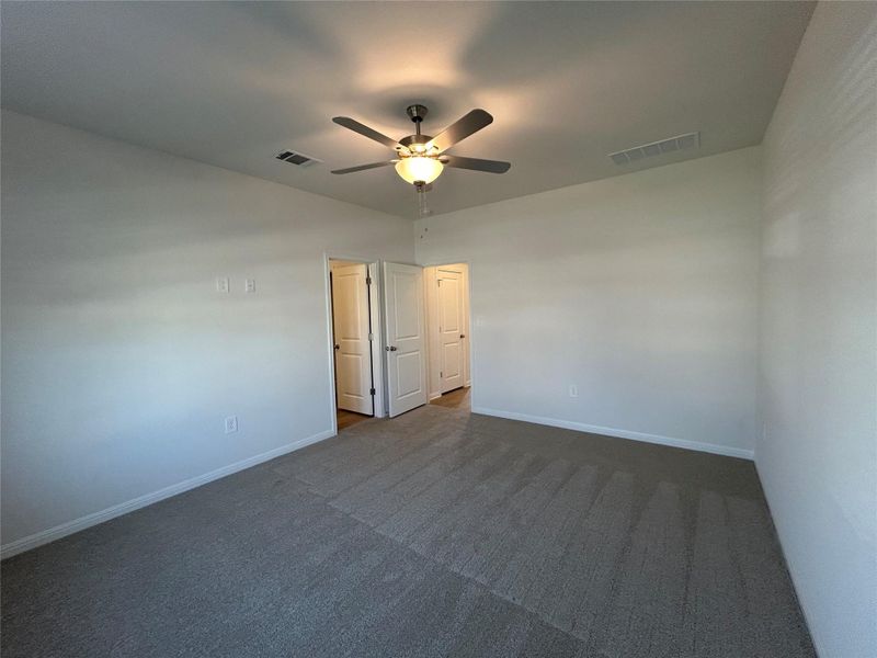 Unfurnished room featuring dark colored carpet and a ceiling fan