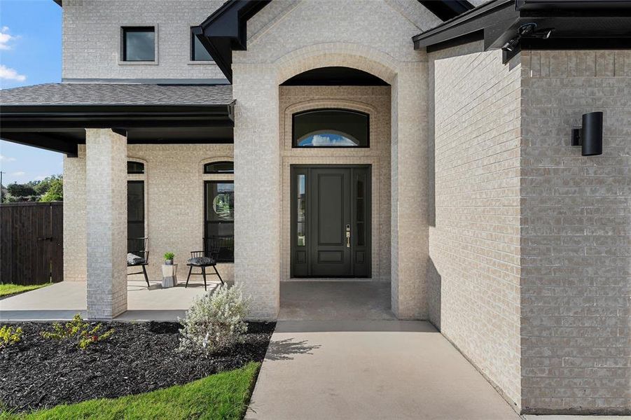 Doorway to property featuring brick siding, a porch, and roof with shingles Doorway to property featuring brick siding, a porch, and roof with shingles