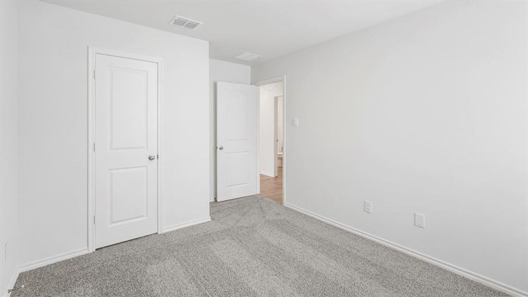 Carpeted room featuring white walls, white baseboards, and white two-panel doors with brushed nickel hardware