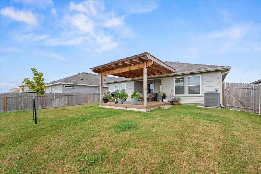 A charming wooden pergola shades the back patio, offering a serene outdoor living space.