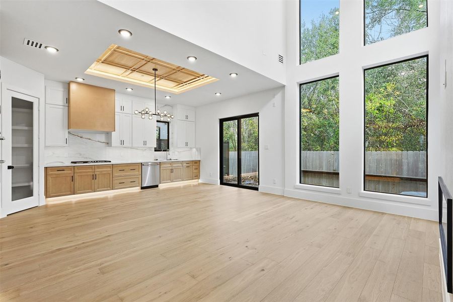 The open-concept kitchen is equipped with flat-panel wood cabinetry, professional-grade appliances, and floor-to-ceiling windows.