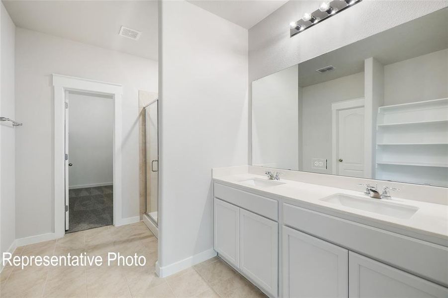 The bathroom features a double vanity with white cabinetry and countertops, a large mirror, and a glass-enclosed shower