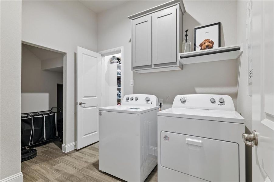 Washroom featuring cabinets, light hardwood / wood-style flooring, and washing machine and clothes dryer