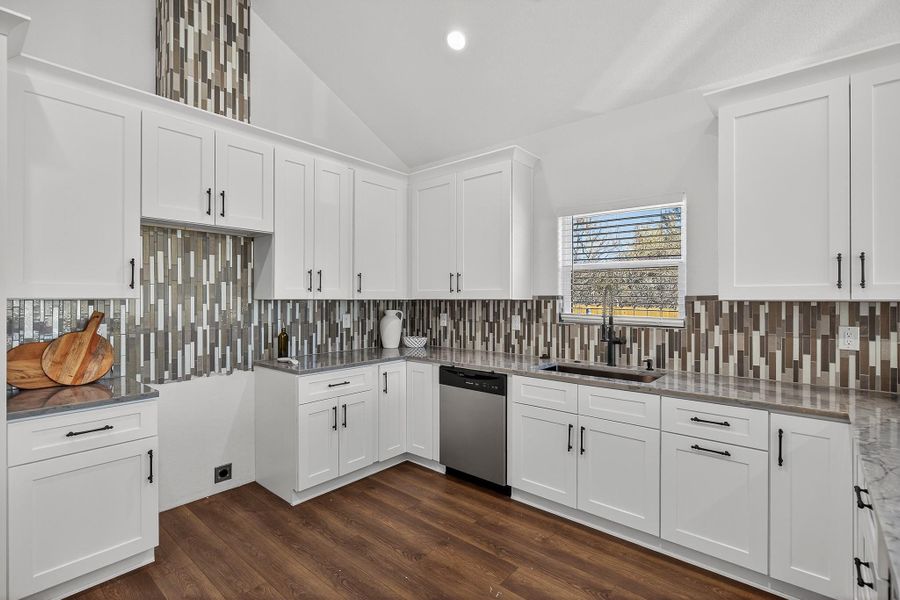 Kitchen featuring vaulted ceiling, white cabinets, dishwasher, dark wood-style floors, and recessed lighting Kitchen featuring vaulted ceiling, white cabinets, dishwasher, dark wood-style floors, and recessed lighting