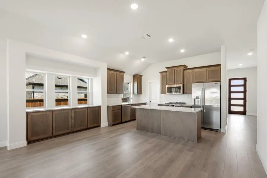 Kitchen with brown cabinets, center island, granite countertops, stainless steel appliances, and light wood floors Kitchen with brown cabinets, center island, granite countertops, stainless steel appliances, and light wood floors